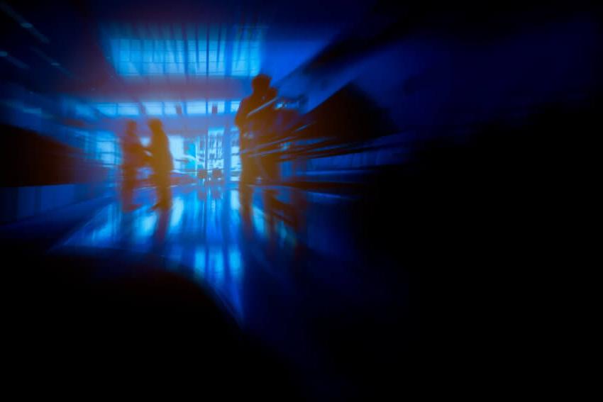 Dark blue and black image of silhouetted healthcare workers in a hospital reception